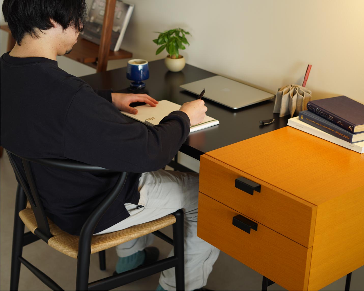 ピエール・ポランデスクとCARL HANSEN & SON （カール・ハンセン＆サン）CH24(Yチェア）ソフトブラック/ビーチに座っている男性